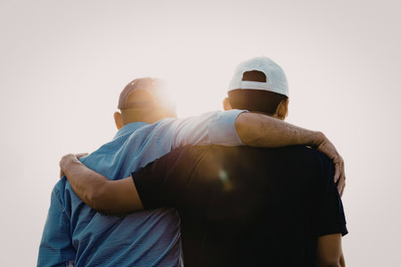 A heartwarming image of two individuals embracing each other against the backdrop of a setting sun. The sun's rays create a warm and serene atmosphere, highlighting the emotional connection between the two people.の写真素材