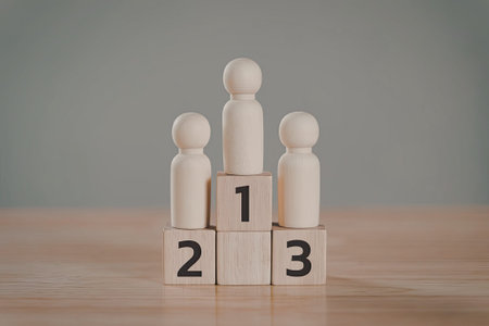 Three wooden figures standing on wooden blocks with the numbers 1, 2, and 3. The figures are arranged in a row, with a plain background.の写真素材