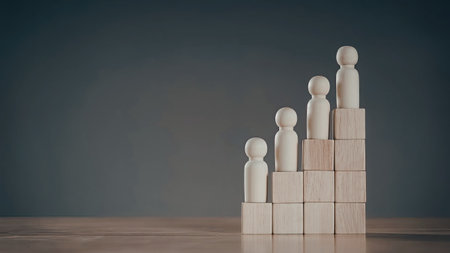 A stack of wooden blocks with small wooden figurines placed on top, against a blue background.の写真素材