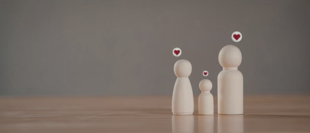 An image featuring three wooden peg dolls representing a family, each with a heart above their heads, set against a plain background.の写真素材