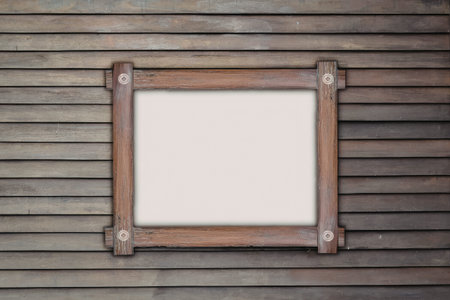 The image depicts a weathered wooden wall with an empty wooden-framed window. The window is square-shaped with a simple wooden frame and is set against a backdrop of aged wooden planks.の写真素材