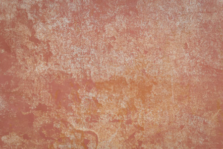 A close-up view of a rustic wall featuring a warm, earthy texture with shades of red and orange. The...