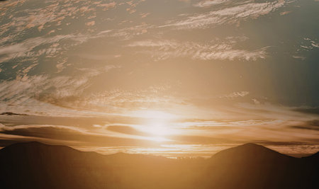 A breathtaking sunset with the sun partially obscured by clouds, casting golden rays across the sky.