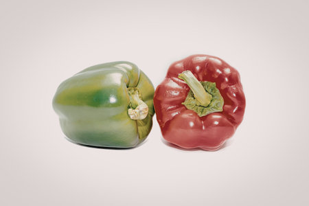 A green bell pepper and a red bell pepper are placed side by side on a plain white background.