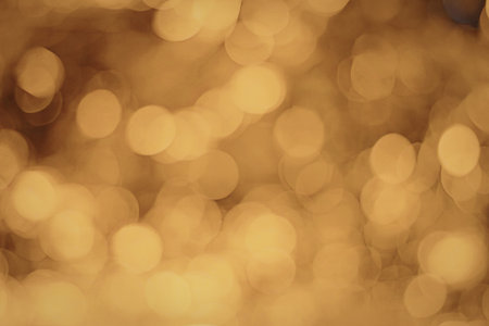 A close-up image of warm, golden bokeh lights creating a soft, blurred background effect. The lights...