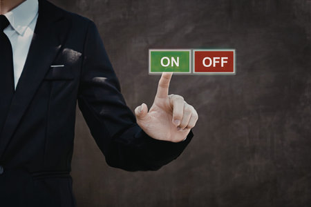 A businessman in a suit is pointing to a green ON button and a red OFF button, indicating a...