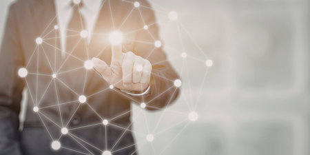 A close-up image of a businessman in a suit using a digital interface, interacting with a network of interconnected nodes and lines, symbolizing technology and innovation.の写真素材