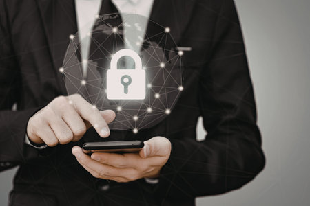 A close-up image of a businessman in a suit holding a smartphone with a security lock symbol...