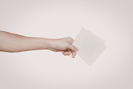 A close-up image of a hand holding a transparent sheet against a white background.