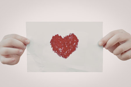 An image of a pair of hands holding a piece of paper with a red heart drawn on it, symbolizing love...