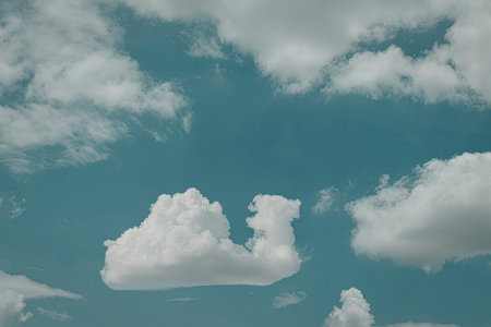 A clear blue sky with scattered, fluffy white clouds. The image captures the tranquility and vastness of the sky, emphasizing the beauty of nature.の写真素材