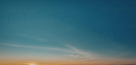 A tranquil image capturing the early morning sunrise with a clear blue sky and wispy clouds.