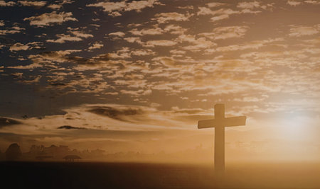 A silhouette of a cross stands prominently against a vibrant sunset, with the sun partially obscured...