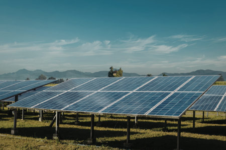 A vast array of solar panels installed in a lush green field, set against a backdrop of mountains...