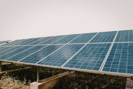 A series of solar panels installed on a rooftop, capturing sunlight under a clear sky. The panels...