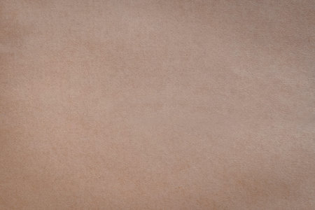 A close-up view of a soft beige textured background featuring subtle variations in color and...