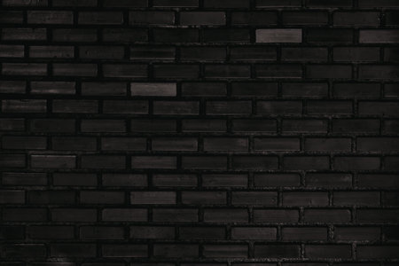 A close-up view of a dark brick wall with a uniform pattern and consistent lighting.