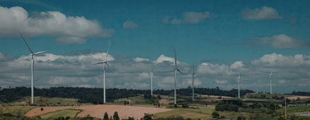 An image showcasing multiple wind turbines standing tall in a vast, open rural landscape under a...