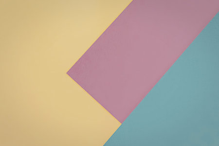 A close-up image of three overlapping color blocks in yellow, pink, and blue against a white...