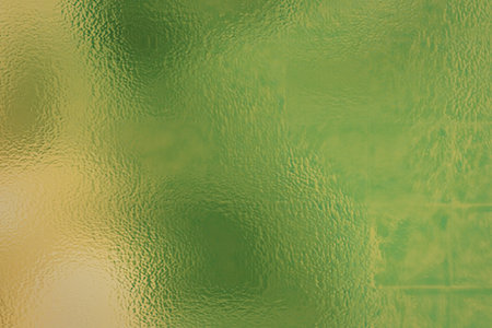A visually appealing abstract background featuring a gradient of green and yellow hues with a metallic texture, creating a dynamic and eye-catching visual effect.の写真素材
