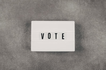 A white rectangular sign with the word 'VOTE' on a gray backgroundの写真素材