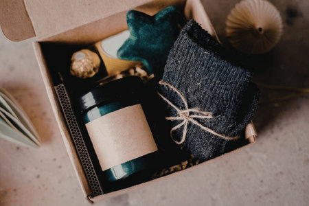 A box containing a green bottle, a dark gray towel, a green velvet item, and other self-care products.の写真素材