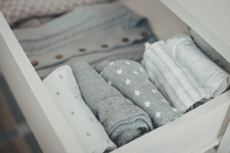 A white drawer containing neatly folded clothes with various patterns and textures.の写真素材