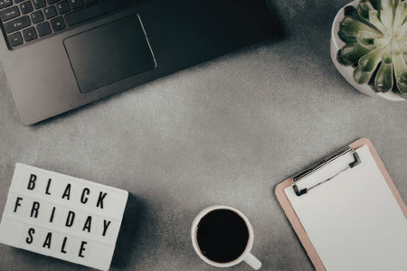 A workspace setup for Black Friday sales planning with laptop, coffee, and clipboardの写真素材