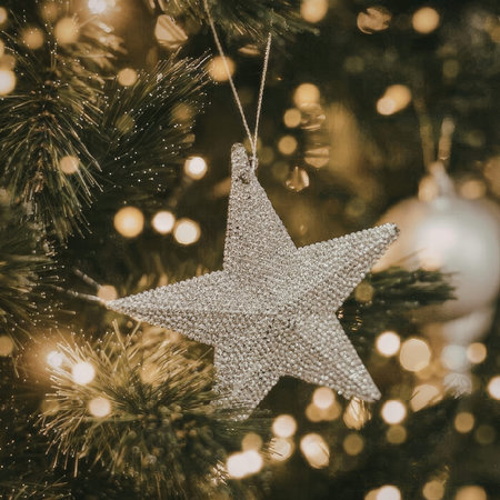 A close-up of a Christmas tree with a star ornament and lightsの写真素材