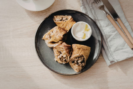 A plate of food with a small bowl of sauce on the side, accompanied by utensils on a napkin.の写真素材