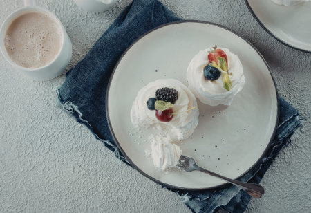 Two meringue desserts on a plate with fresh fruits and whipped creamの写真素材