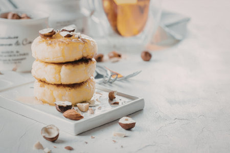 A stack of pancakes on a white plate with nuts and syrupの写真素材
