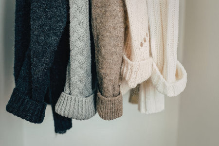 A collection of sweaters in various colors hanging on a closet rod.の写真素材