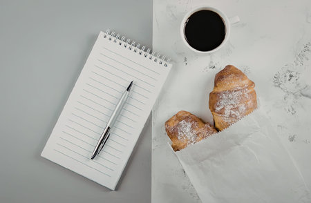 A setup for a quiet morning with coffee, croissants, and a notepad.の写真素材
