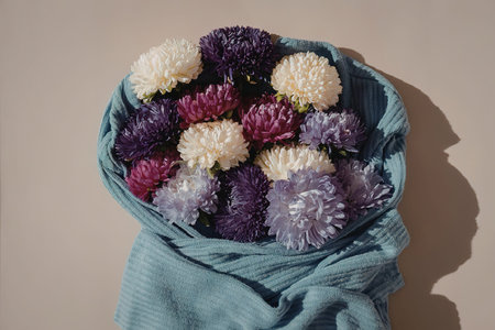 A bouquet of purple, pink, and white chrysanthemum flowers wrapped in blue cloth