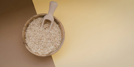 A bowl filled with oats and a wooden spoon on a brown and yellow backgroundの写真素材