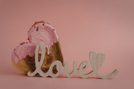 A chocolate cupcake with pink frosting and a decorative 'love' sign in front of it.