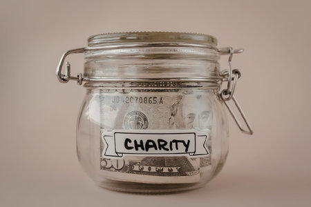 A clear glass jar with a metal clasp and a label that reads 'CHARITY' in black letters on a white...