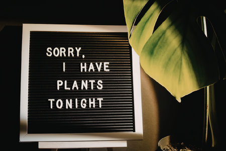 A sign that reads 'I have plants tonight' next to a large green leafy plant, suggesting a night in...