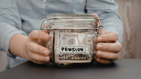 A person holding a glass jar labeled pension with money inside