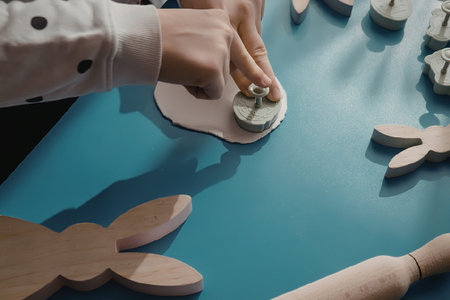 A child's hand assembling a wooden puzzle on a blue table with various wooden pieces.