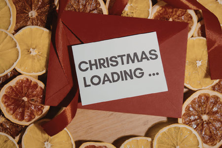 A red gift box with a 'Christmas Loading...' message surrounded by dried citrus fruits.の写真素材