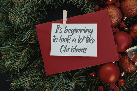 A red envelope with a white tag that reads 'It's beginning to look a lot like Christmas' surrounded...