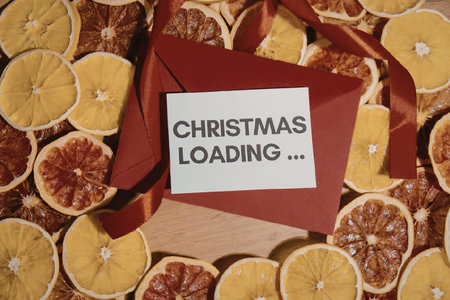A red gift box with a white label reading 'CHRISTMAS LOADING...' surrounded by dried slices of orange and blood orange.の写真素材