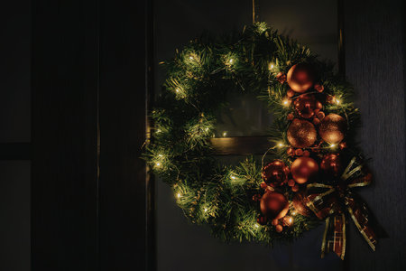 A Christmas wreath adorned with green lights, a red bow, and hanging on a doorの写真素材