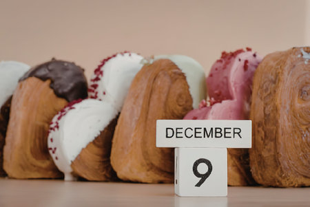 A row of assorted madeleines with various toppings on a table with a calendar showing December 9.