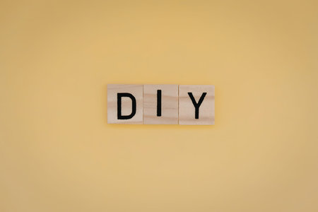 A DIY concept represented by wooden blocks on a yellow backgroundの写真素材