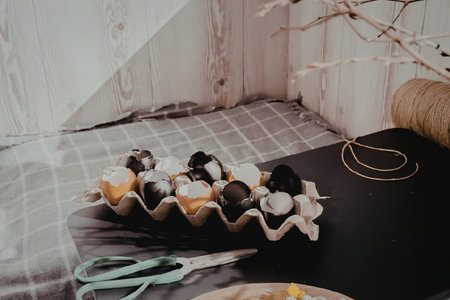 A bowl of colorful Easter eggs on a table with crafting supplies