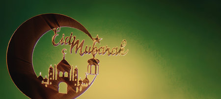 A festive background image featuring a crescent moon, mosque, and the words 'Eid Mubarak' in gold, set against a green gradient backdrop.の写真素材