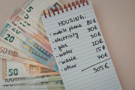 A handwritten note listing housing expenses next to euro banknotes
